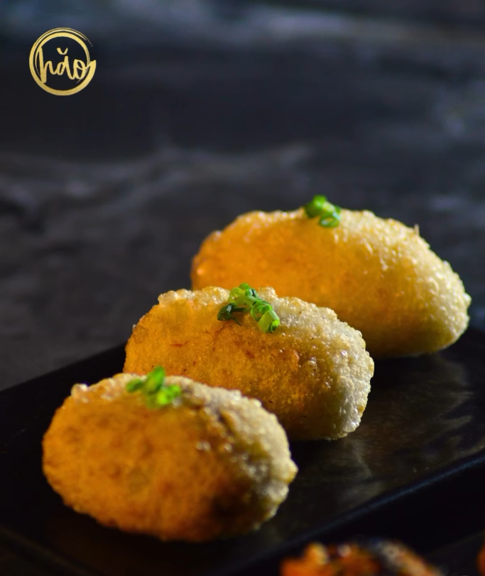 Golden crispy ham sui gok dumplings on a dark plate