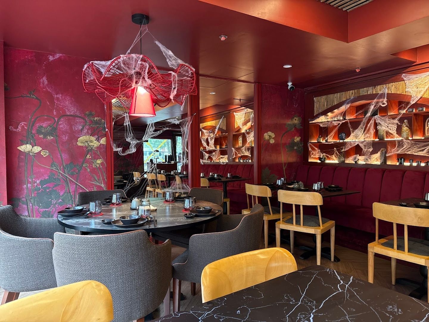 hăo interior with red walls, artistic chandelier, and warm dining ambiance